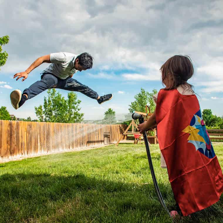 Man jumping above a stream of hose water